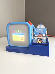 an alarm clock is sitting next to a toy boat on a blue stand with a white background