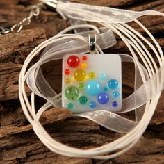 a multicolored glass bead necklace on a white cord with a ribbon around it