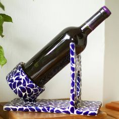 a blue and white vase with a wine bottle in it sitting on a wooden table