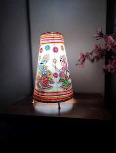 a lamp that is sitting on top of a table next to a vase with flowers