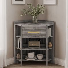 a corner table with two framed pictures on the wall and a vase filled with flowers