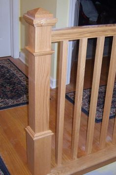 a wooden bannister in the middle of a hardwood floored area with rugs