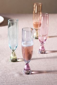 three different colored glasses sitting on top of a table next to plates and utensils