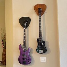 two guitars are hanging on the wall next to each other, one purple and one black