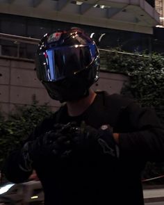 a man wearing a motorcycle helmet and holding his hands out to the side while standing in front of a building