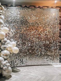 a room filled with lots of silver and white balloons in front of a mirror wall