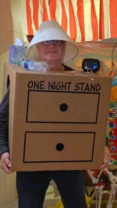 a person holding a cardboard box with one night stand on it's head and wearing a white hat