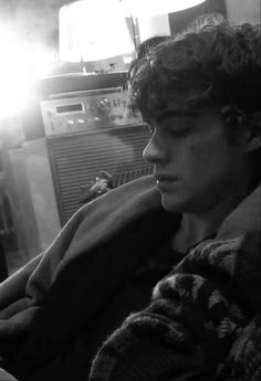 a young man sitting on top of a couch next to an old fashioned radio set