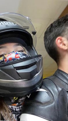 a person wearing a helmet and bandana covering their face next to a man in a leather jacket