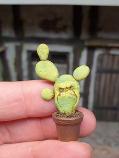 a tiny toy is sitting on top of a small potted plant in someone's hand