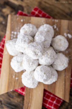 a wooden cutting board topped with snowball cookies