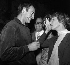 black and white photograph of two people touching each other's foreheads while others look on