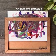 the complete bundle is displayed in a wooden frame on a table next to a potted plant