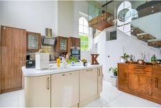 a kitchen with white counter tops and wooden cabinets in the center, along with stairs leading up to the second floor