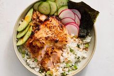 a bowl filled with rice, cucumbers, and other vegetables on top of it