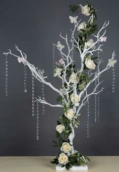 a tall white tree with flowers and chains hanging from it's branches, in front of a gray background