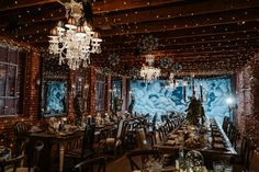 a dining room set up for an event with lights on the ceiling and chandeliers hanging from the ceiling