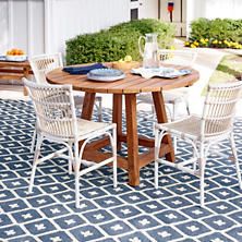 an outdoor table with chairs and plates on it in front of a white house,