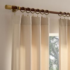 the curtains are hanging on the rod in front of an open window with sunlight coming through