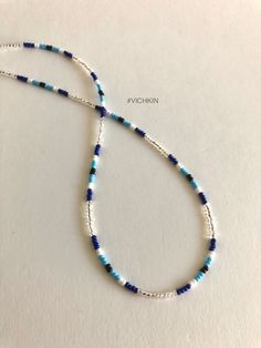 a blue and white beaded necklace on a white surface with the words,'i am