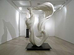 an abstract sculpture is in the middle of a room with white walls and wood floors