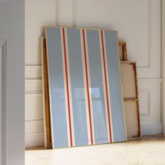 a blue and red striped frame sitting on top of a hard wood floor next to an open door