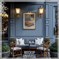 two chairs and a table in front of a blue building with an advertisement on the wall