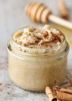 a jar filled with cinnamon butter and topped with whipped cream next to some cinnamon sticks