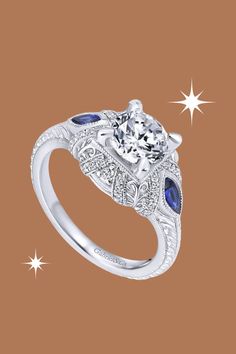 Celebrate timeless romance with the Gabriel "Lexington" Vintage Style Diamond and Blue Sapphire Halo Diamond Engagement Ring. This exquisite ring features 0.15 carats of round-cut diamonds and 0.40 carats of marquise-cut blue sapphires, forming a captivating halo. Milgrain details add a touch of vintage charm to the design. Meticulously crafted by Gabriel, this engagement ring is a radiant expression of sophistication and enduring love. Sapphire Halo Engagement Ring, Halo Diamond Engagement Ring, Halo Engagement Ring, Halo Engagement, Halo Diamond, Diamond Engagement Ring, Blue Sapphire, Diamond Engagement, Halo