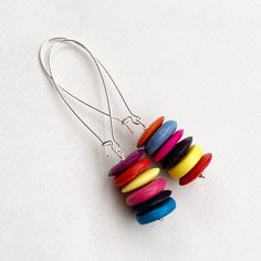 These colorful dangle earrings have a unique tropical flair!  A stack of six turquoise howlite heishi beads in shades of plum purple, red, orange, yellow, hot pink and blue dangle from silver plated kidney ear wires. These earrings measure approximately 3 inches in length.  A fabulous look! Item is carefully packaged and shipped via USPS in a sturdy protective mailer. Check out more fabulous jewelry and enter my shop here: https://www.etsy.com/shop/jewelbytessyla View the positive feedback I've received from customers and check out some beautiful art prints for nursery and home at my print shop, Tessyla: https://www.etsy.com/shop/Tessyla Thanks for looking and have a great day! Long Colorful Earrings, Colorful Dangle Earrings, Tropical Earrings, Colorful Bead Earrings, Multicolor Earrings Tropical Earrings, Multicolor Earrings, Earrings Colorful, Earrings Purple, Turquoise Howlite, Colorful Earrings, Heishi Beads, Fabulous Jewelry, Plum Purple