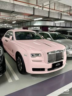 several cars parked in a parking garage with one pink car on the right side and another black car on the left