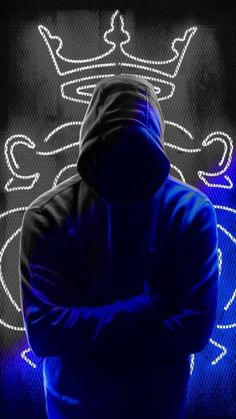 a man standing in front of a neon sign wearing a hoodie and holding his arms crossed