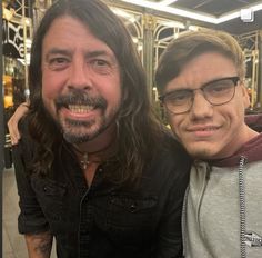 two men with long hair and glasses posing for a photo