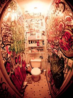 a bathroom with graffiti all over the walls and toilet in the middle of the room