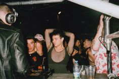 a group of people at a party with dj's in the back ground and one person wearing headphones