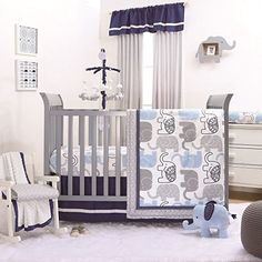 a baby crib with blue and gray bedding in a nursery room, next to a window