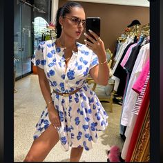 a woman taking a selfie in front of a mirror while wearing a dress with blue flowers on it