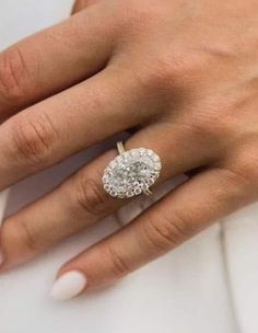 a woman's hand with a diamond ring on her finger and white manicured nails