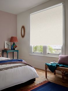 a bedroom with pink walls, white bedding and blue rugs on the floor