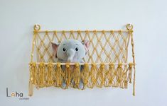 an elephant stuffed animal sitting on top of a yellow net hanging from the side of a wall