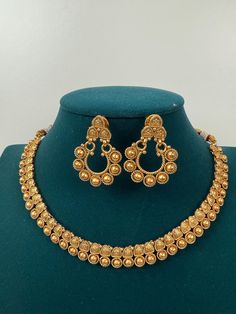 This exquisite piece of craftsmanship comes from our Traditional collection. Finish: 24 grams gold finish Necklace Fastening: Adjustable Dori Earring Fastening: Push Back Contains: 1 necklace, 1 pair of earrings Elegant Antique Gold Necklaces For Festivals, Elegant Antique Gold Necklace For Festivals, Gold Necklaces With Elegant Design For Anniversary, Antique Gold Brass Necklace For Wedding, Gold Chandbali Temple Jewelry Necklace, Antique Gold Necklace With Intricate Design For Weddings, Antique Gold Brass Jewelry For Wedding, Elegant Antique Gold Chandbali Necklaces, Gold Necklace With Elegant Design For Festive Occasions