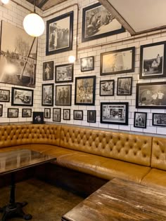 a corner booth with leather couches and pictures on the wall behind it in a restaurant