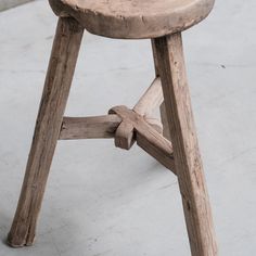 a wooden stool sitting on top of a cement floor