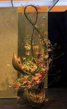 a vase filled with lots of flowers on top of a wooden table next to a wall