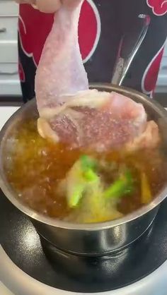 a person is stirring soup in a pot on the stove top with a ladle