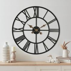 a clock that is on the side of a wall next to a vase with flowers