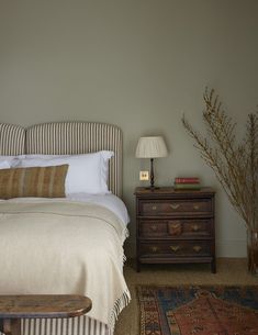 a bed sitting next to a wooden dresser with a lamp on it's side