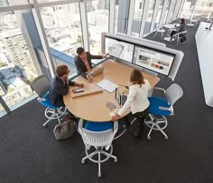 three people sitting at a round table in an office