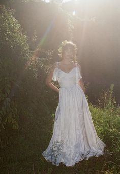 a woman wearing a white dress standing in the grass