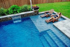 a woman lounging in a chair next to a swimming pool with fire pit and patio furniture